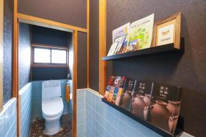 a bathroom with a toilet and books on the wall at サウナ&ステイ吉日荘-益子町のプライベートサウナ付の貸切古民家 BBQ 高速Wi-fi in Mashiko