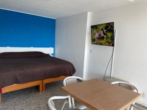 a bedroom with a bed and a table with chairs at Bonita Suite Torres Gemelas in Acapulco
