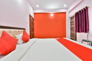 a bedroom with a large bed with an orange wall at Hotel O Magadh Imperial in Patna