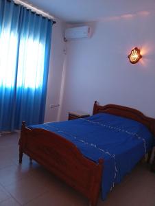 a bedroom with a bed with a blue blanket and a window at Résidence R in Salakta