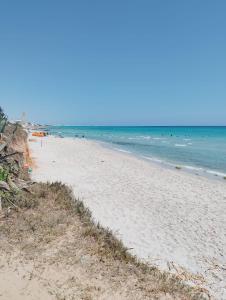 a sandy beach with people in the water at Résidence R in Salakta