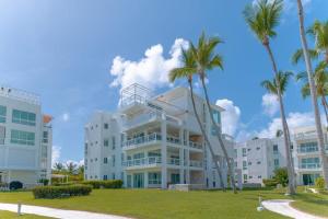 a large white building with palm trees in front of it at Beachfront Luxury Condo PGA Ocean View 4BR in Boca del Soco