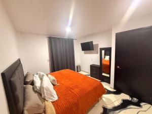 a bedroom with a bed with an orange blanket at Apartamento Maywood in Zacatecas