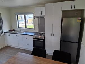 a kitchen with white cabinets and a stainless steel refrigerator at Spring Creek Holiday Park in Blenheim +37 photos