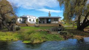 a house with a river in front of it at Spring Creek Holiday Park in Blenheim
