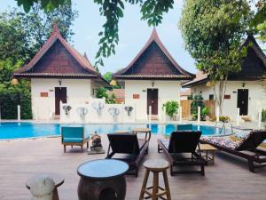a resort with a swimming pool with chairs and tables at Pludhaya Resort & Spa in Phra Nakhon Si Ayutthaya