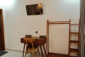 a room with a desk and a television on a wall at The Tamarin Villas in Nusa Penida