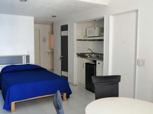 a bedroom with a blue bed and a kitchen at Hermosa Suite Torres Gemelas in Acapulco