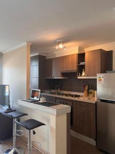 a kitchen with wooden cabinets and a counter with a laptop at Departamento Los Poetas in Temuco