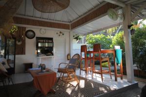 a porch with chairs and a table in a room at New Balengku Dua Hotel - Adults Only in Gili Islands