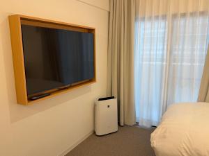 a bedroom with a flat screen television on the wall at レジデグローバル熊本 in Kumamoto