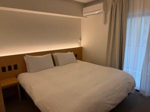 a bedroom with a large white bed with a window at レジデグローバル熊本 in Kumamoto +8 photos