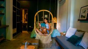 a woman sitting in a wicker chair reading a book at Happiness Villas in El Nido