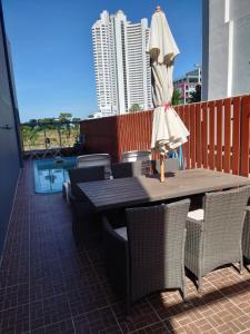 a table and chairs with an umbrella on a balcony at Baan der Bruyn in Jomtien Beach