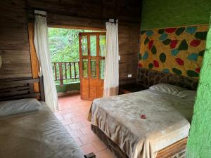 a bedroom with two beds and a window with a door at Hotel El Santuario in Minca