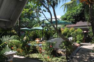 a garden with green umbrellas and flowers at New Balengku Dua Hotel - Adults Only in Gili Islands