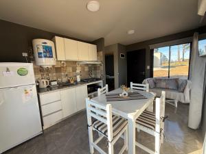 a kitchen with a table and a white refrigerator at El Tesoro de Yacanto in Villa Yacanto +7 photos