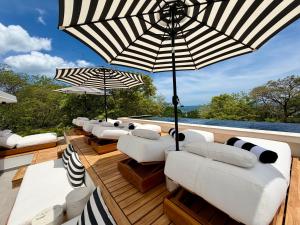 a row of white couches and umbrellas on a deck at NOAM by the sea in Tamarindo