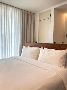 a bedroom with a white bed with a large window at NOAM by the sea in Tamarindo