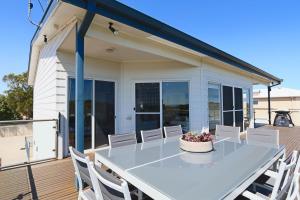 a large white table and chairs on a deck at '128 The Esplanade' - Beachside holiday home with swimming pool in Robe in Robe