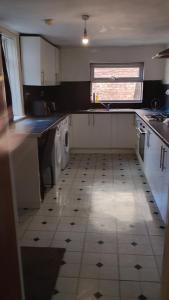 a kitchen with white cabinets and a tile floor at AAA lodge in Middlesbrough