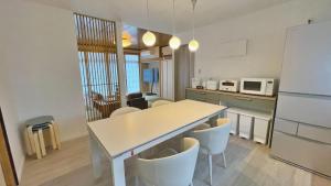 a kitchen with a table and some chairs and a refrigerator at Tabinoteitaku 和-WA- in Sendai