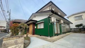 a green and white house on a street at Tabinoteitaku 和-WA- in Sendai