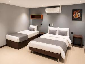 a bedroom with two beds and a wall with a painting at Hotel Laureles Loft in Medellín