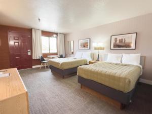 a hotel room with two beds and a desk at Prospector Inn in Escalante