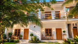 a white house with wooden doors and a palm tree at Royal Palms Resort in Arugam Bay