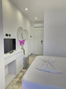 a white bedroom with a bed and a tv at Crown Villa in Golem