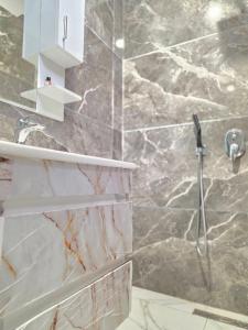 a bathroom with a shower with a marble wall at Crown Villa in Golem