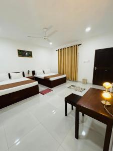 a room with two beds and a table in it at Arcadiaa Villa in Polonnaruwa