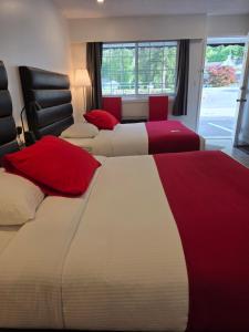 two beds in a hotel room with red and white at Alpine Motel in Hope