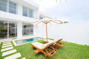 a pair of chairs and an umbrella next to a pool at Blanca Karma Villas in Uluwatu