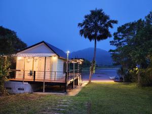 a house with a palm tree next to a river at Porjai's Lakeview in Phetchabun