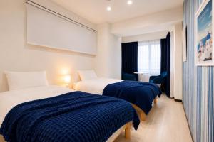 two beds in a room with blue and white sheets at West Press Sasebo in Sasebo