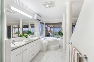 a white bathroom with two sinks and a bath tub at Whale Song House in Bargara +45 photos