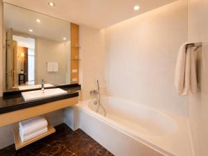 a bathroom with a tub and a sink and a mirror at Urbana Sathorn Hotel, Bangkok in Bangkok