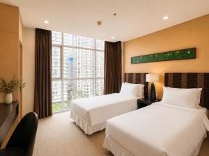 two beds in a hotel room with a large window at Urbana Sathorn Hotel, Bangkok in Bangkok