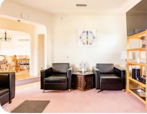 a living room with two leather chairs and a table at Sacred Heart House in Montebello