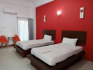 two beds in a room with a red wall at 22 Seasons Hotel in Ban Khlong Chi Lat