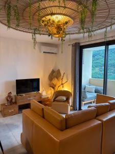 a living room with a couch and a television at Zen escape-ocean view Papeete in Papeete