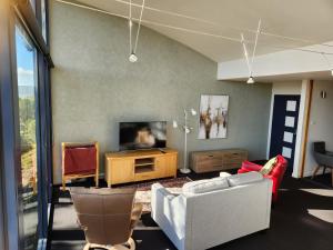 a living room with a couch and a tv at Tamar Ridge Winery Apartments in Grindelwald