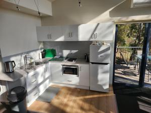 a kitchen with white cabinets and a refrigerator at Tamar Ridge Winery Apartments in Grindelwald +2 photos