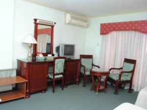 a hotel room with a desk with chairs and a television at DJ Paradise Hotel in Tikay