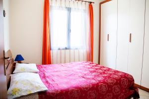 een slaapkamer met een roze bed en een raam bij Appartamento Di Basilia in Bari Sardo