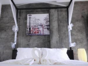 a bedroom with a bed with white sheets and a picture at The Key Hotel in Ko Lipe +34 photos
