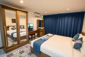 a hotel room with two beds and a desk and a mirror at The Indigo House Phrae in Ban Rong Fong