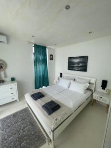 a white bedroom with a large bed and a blue curtain at Krum's Little Secret Villa in Vourvourou